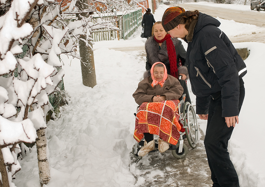 Clearing the snow for an elderly women photo via shutterstock