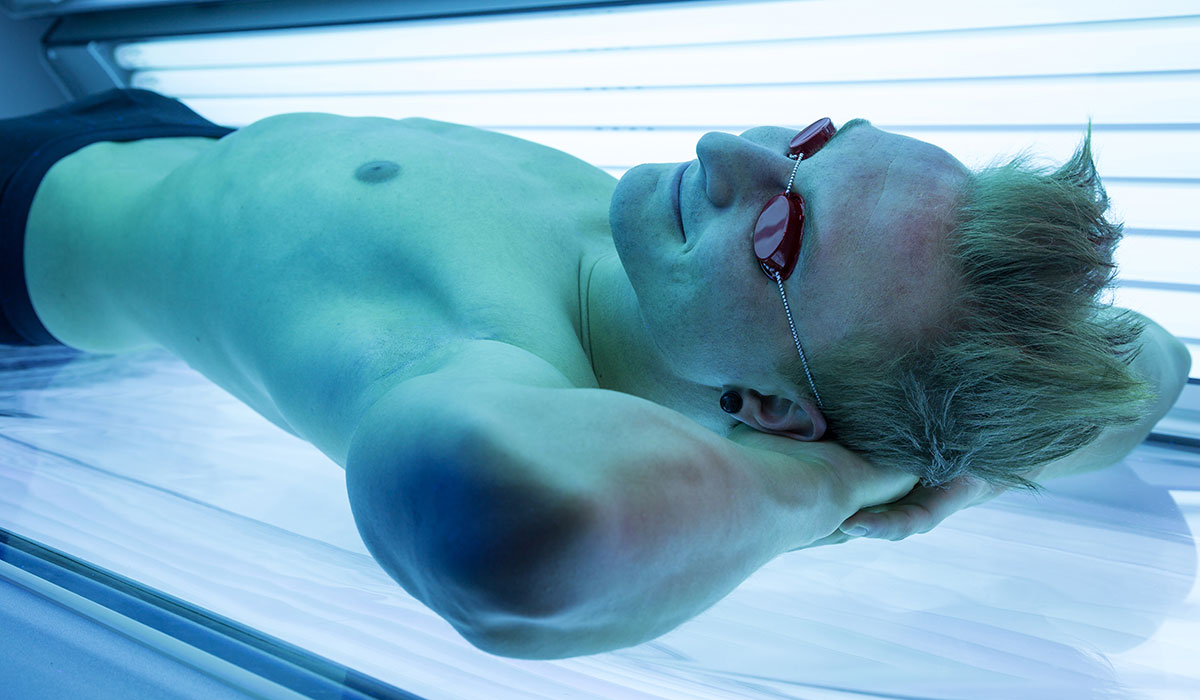 We all know that tanning beds are a no-no. But is spray tanning really a safer alternative? Man in tanning bed image via shutterstock.