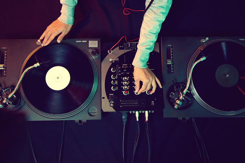 A DJ at the equipment deck via Shutterstock.