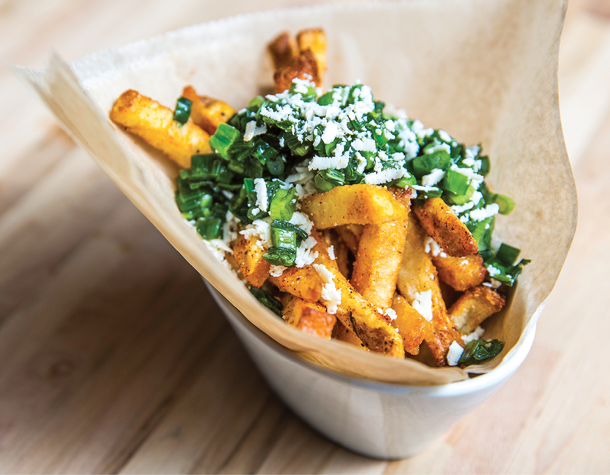 Fries are topped with crumbled cotija cheese and scallion salsa. 