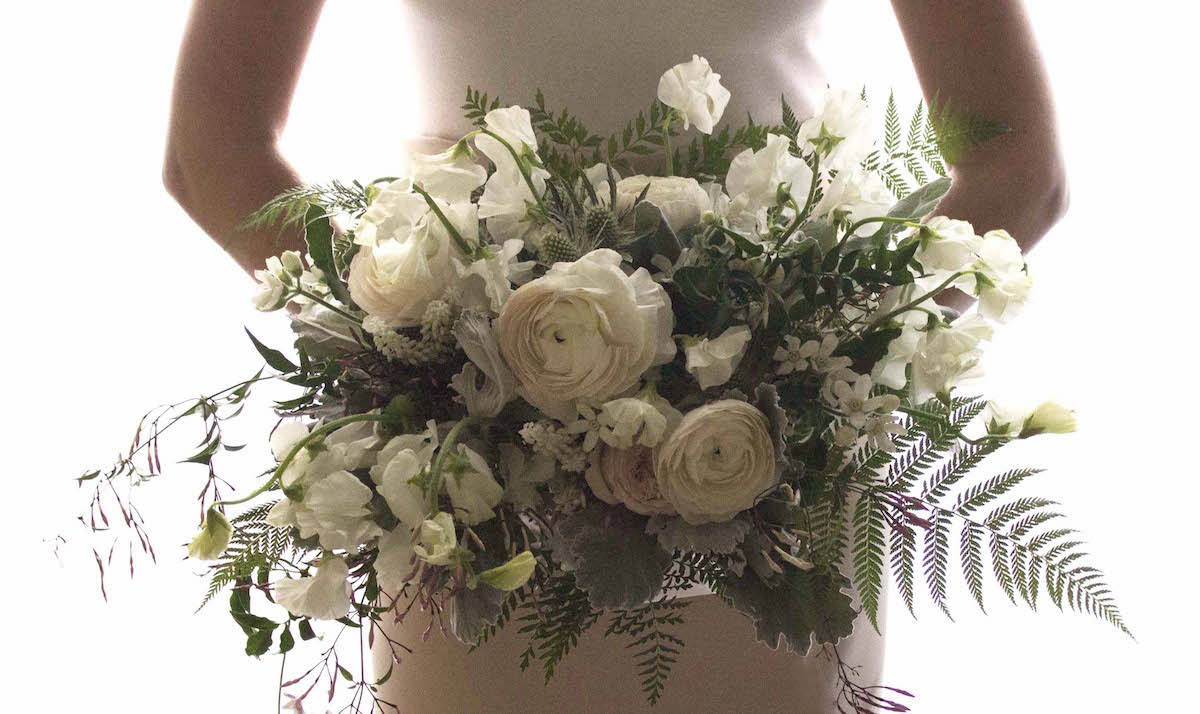 Ranunculus and sweet pea lend a sweet softness to this classic horizontal bouquet; photo courtesy of Winston Flowers