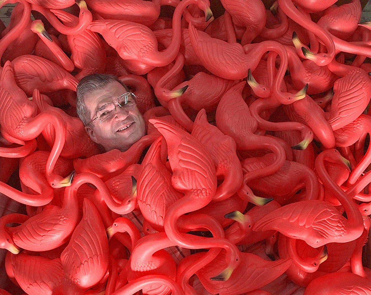 FILE - In this Thursday, June 25, 1998 photo, Don Featherstone, creator of the original plastic pink flamingo, sits surrounded by many of the plastic creatures at Union Products, Inc. in Leominster, Mass. Featherstone died Monday, June 22, 2015, at an elder care facility in Fitchburg, Mass., according to his wife, Nancy. He was 79. (AP Photo/Amy Sancetta)