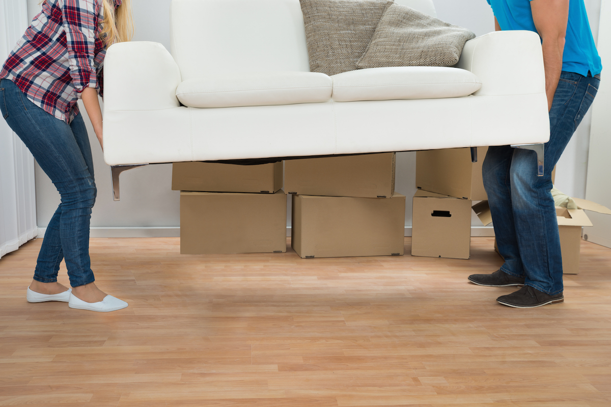 Happy young couple carrying couch in new home via Shutterstock
