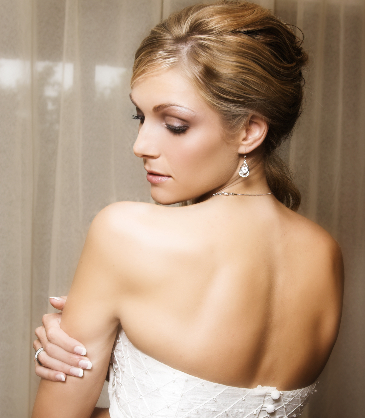 Beautiful Blond bride wearing diamond jewelery looking over her shoulder via Shutterstock