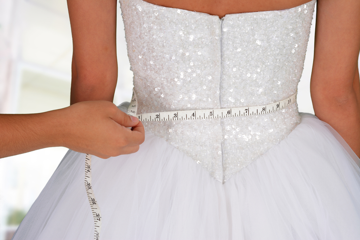 Woman in wedding dress getting measured via Shutterstock