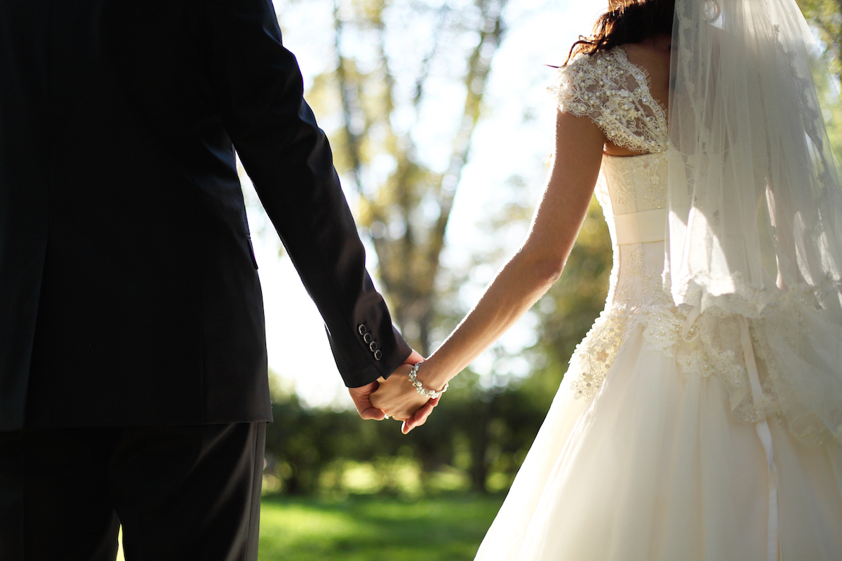 Wedding theme holding hands newlyweds via Shutterstock