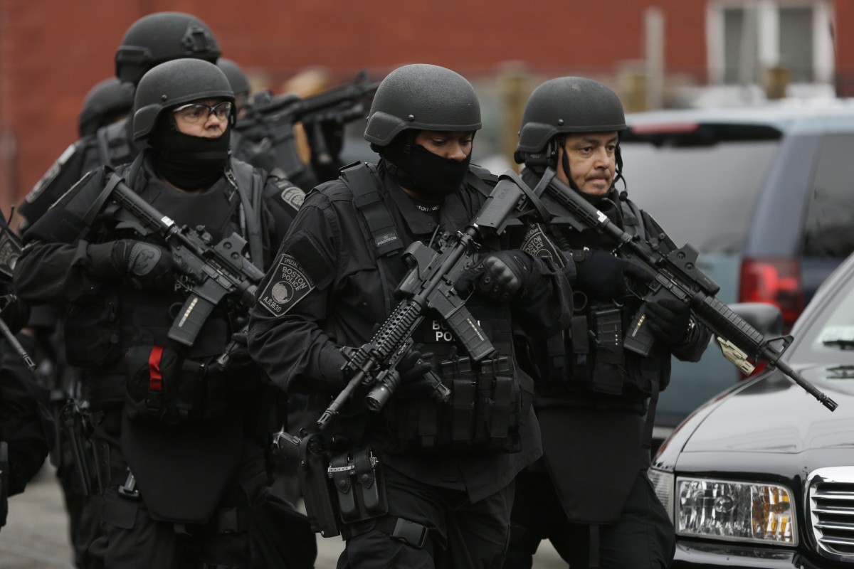 Police in tactical gear conduct a search for a suspect in the Boston Marathon bombings, Friday, April 19, 2013, in Watertown, Mass. The bombs that blew up seconds apart near the finish line of the Boston Marathon left the streets spattered with blood and glass, and gaping questions of who chose to attack and why. (AP Photo/Matt Rourke)