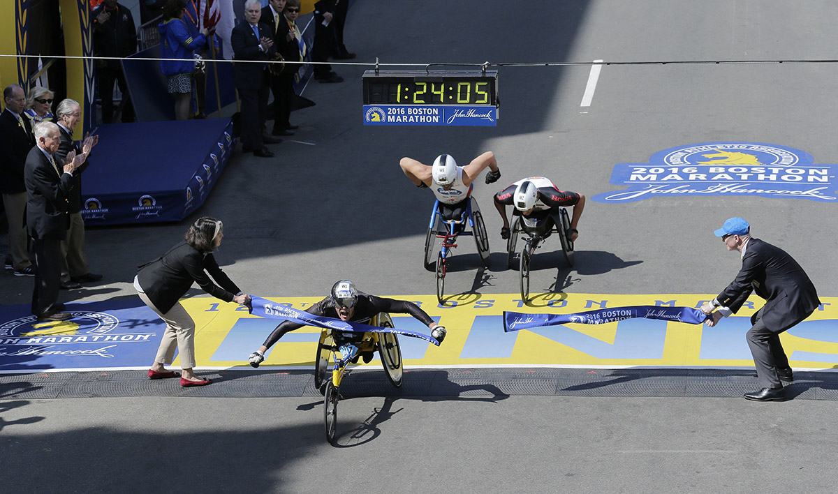 Marcel Hug, of Switzerland, breaks the tape ahead of Kurt Fearnley and Ernst Van Dyk. / Photo via AP