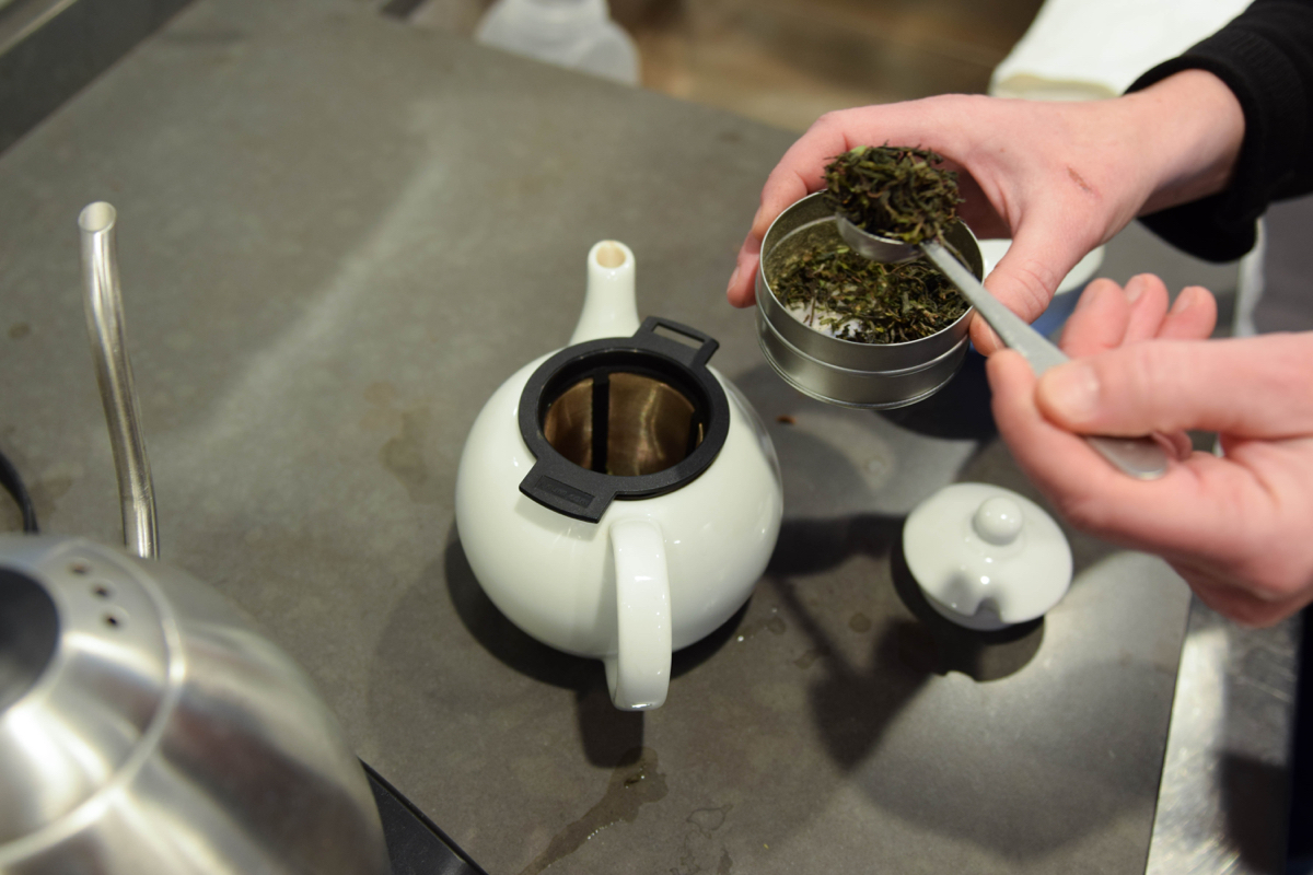 After swilling hot water around the teapot to warm it, Scalise adds her chosen tea leaves. She chose a Darjeeling first flush; the first harvest of tea leaves from an Indian darjeeling variety. Darjeeling tea is also known as “The Champagne of Tea.” / Photo by Lloyd Mallison