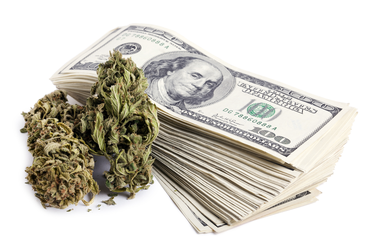 Marijuana buds and a large stack of 100 US dollar money notes isolated on white background.