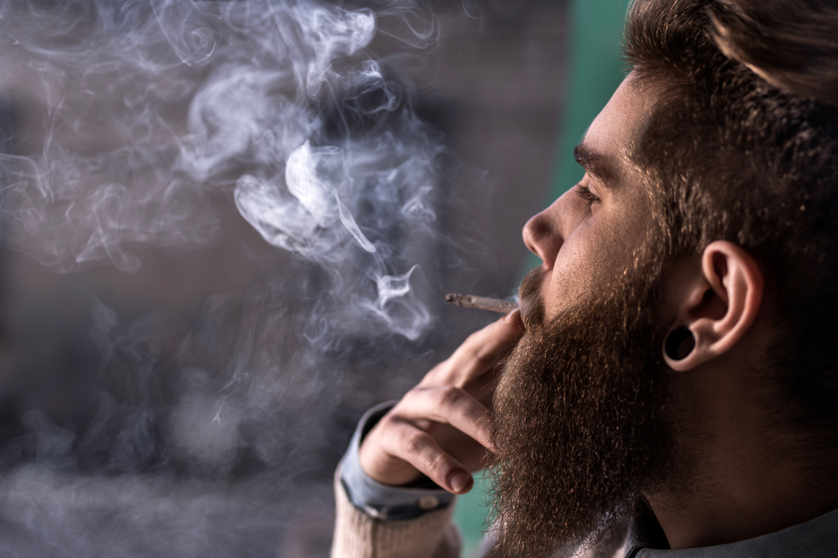 Close up of hipster man smoking weed cigarette.