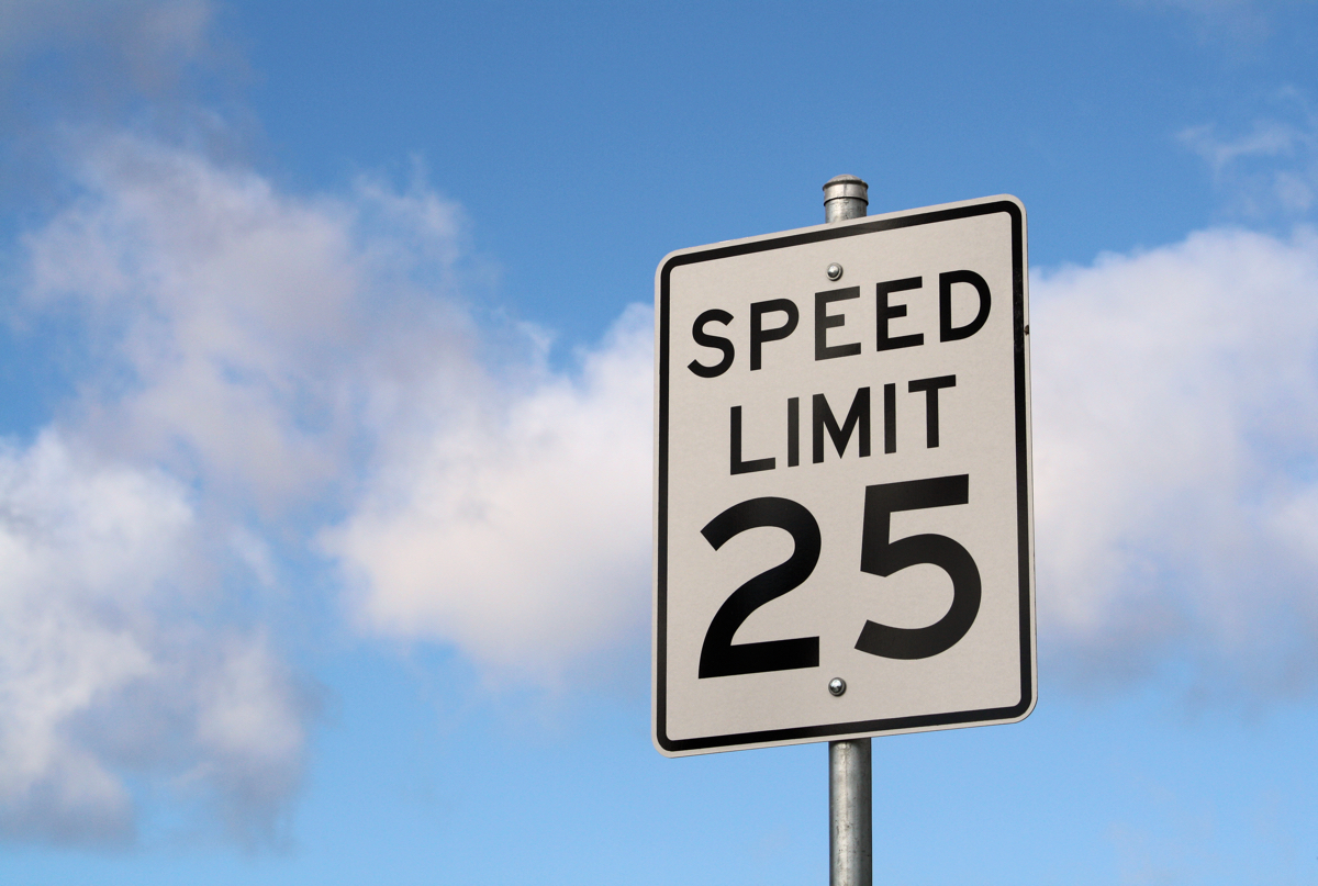 A 25 MPH speed limit sign highlighted by a blue sky in the background.