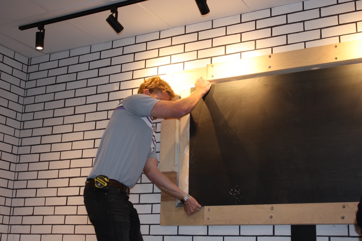 A contractor with Cafco Construction Management installs Blackbird Doughnuts' new chalkboard menu in Fenway. / Photos by Jacqueline Cain