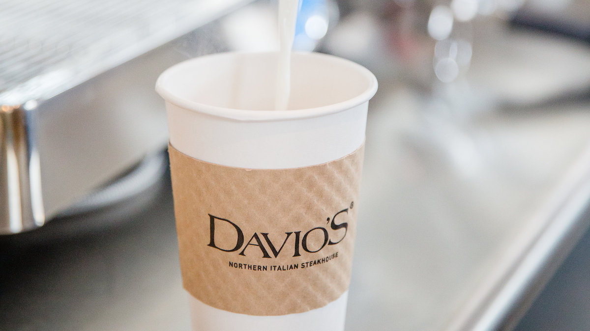 Steamed milk poured into a hot beverage cup labeled "Davio's"