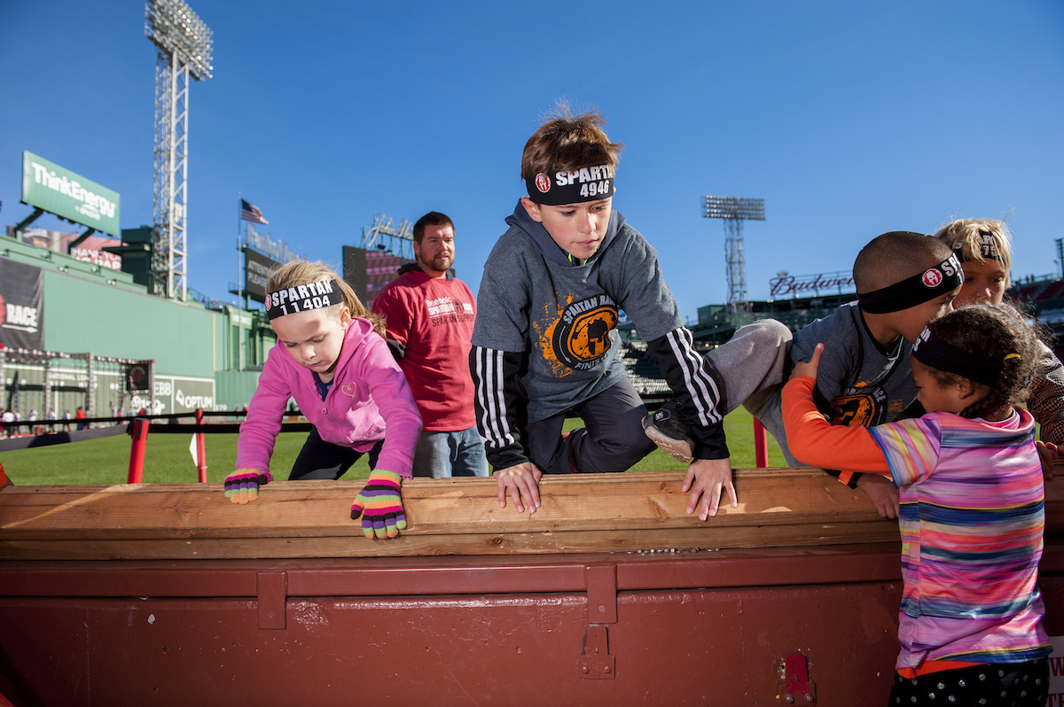 Kids climb over a wall at Fenway Park