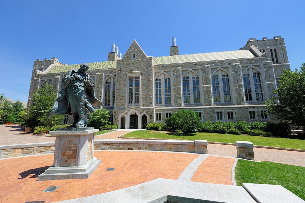 The Saint Ignatius Loyola statue in front of a grand building on the Boston College campus