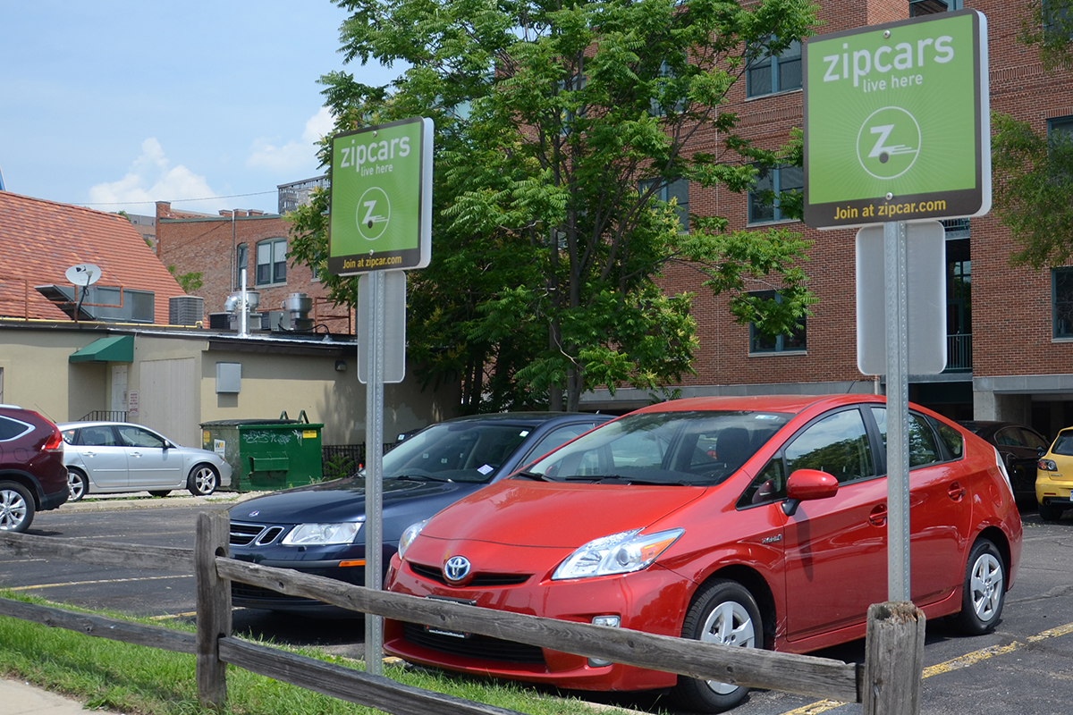 Two cars sit in a Zipcar parking lot