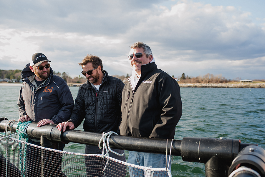 (L to R) Row 34 group purchaser Phil Peterson, UNH and N.H. Sea Grant aquaculture specialist Michael Chambers, and Row 34 chef/partner Jeremy Sewall on the floating platform of the steelhead trout farm
