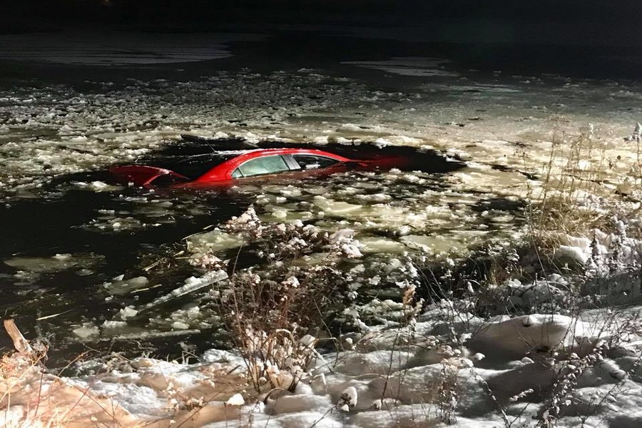 A red car sinking into an icy pond