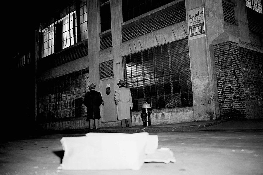 Two unidentified people look at entrance of Brink's Inc., an armored truck firm's garage on Prince Street, in Boston, Massachusetts, Jan. 17, 1950, where seven gunmen tied up five employees and robbed an open vault of "more than $500,000 in cash." Police, reconstructing the holdup, said the robbers reached the vault on the second floor of the garage by opening six locked door, "probably with a passkey." 