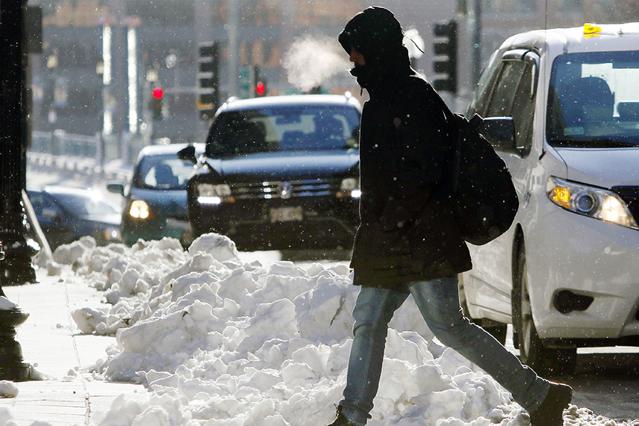 A man walks bundled up through a snowy intersection