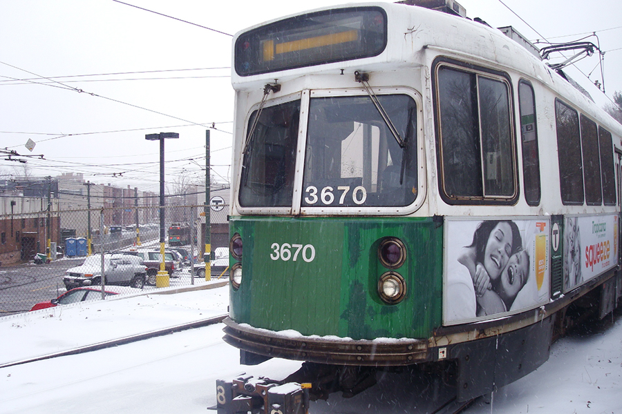 A green line train travels through a snowy terrain