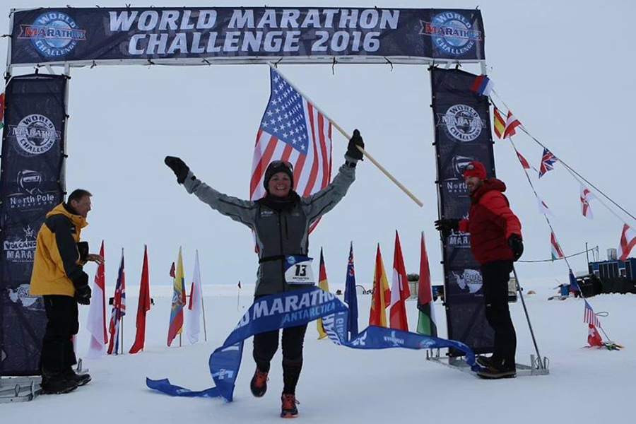 A woman crosses the finish line of a marathon wearing a lot of cold gear