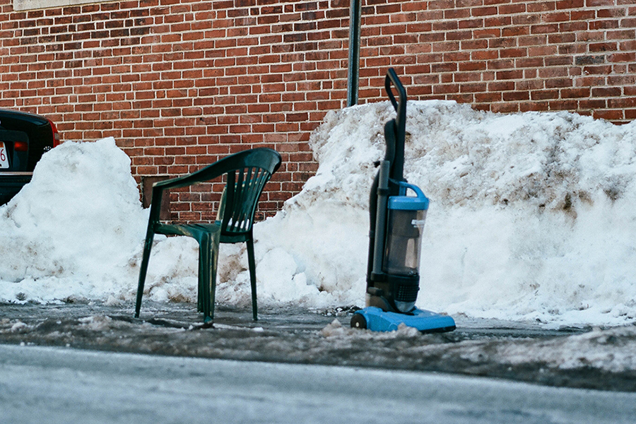 A lawn chair and vacuum cleaner in shoveled-out parking spots