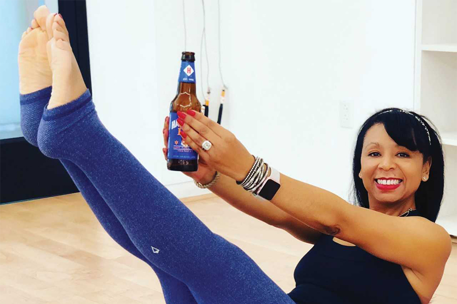 Monica Huaza leads a beer yoga class holding a beer bottle in a full upright position