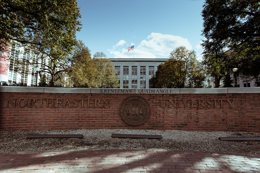 A brick wall with the Northeastern University name and crest