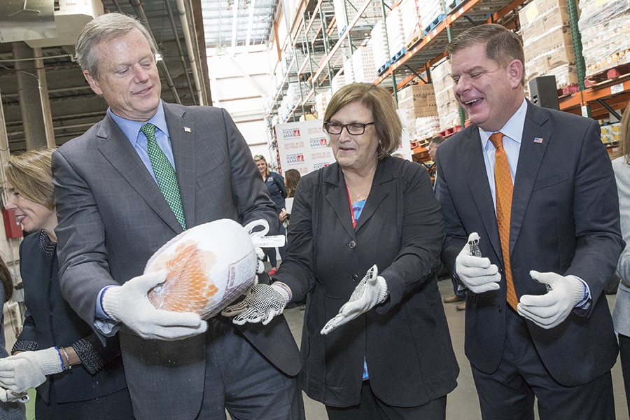 Charlie Baker holds a turkey while Catherine D'Amot and Marty Walsh look on