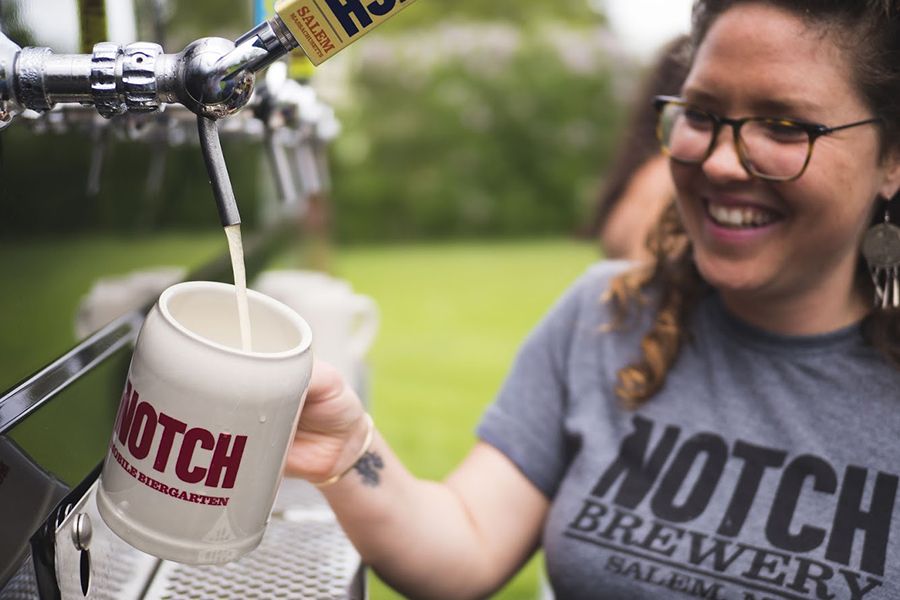 A bartender pours a mug of Notch beer at a mobile biergarten event with the Trustees