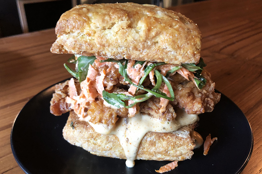 Fried chicken sandwich with collard greens coleslaw on a cornbread biscuit at Idle Hour