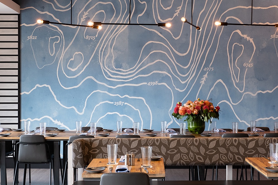 The far wall of the private dining room at Alcove is decorated with a bright blue topographical map