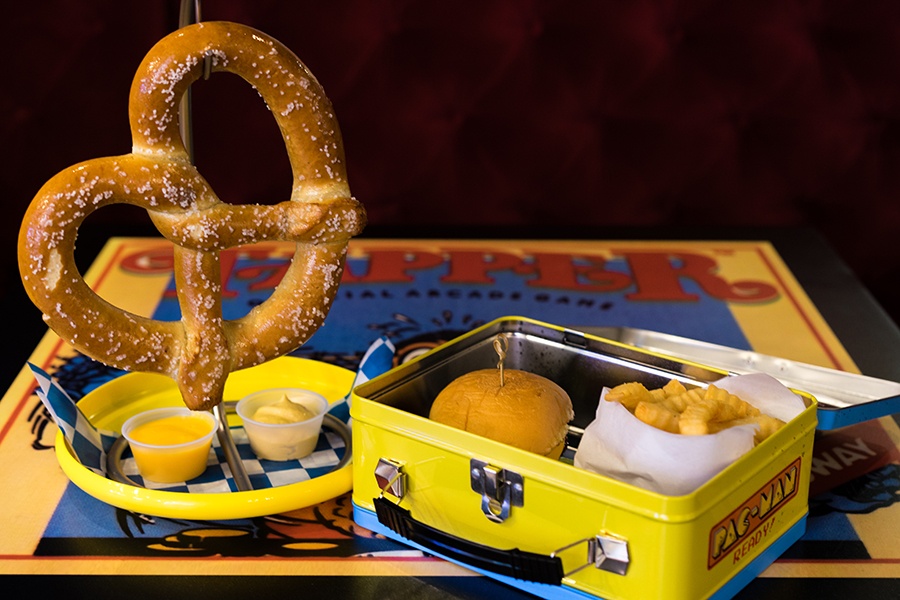 a soft pretzel and a hamburger and crinkle fries in a retro lunchbox at Versus in Boston