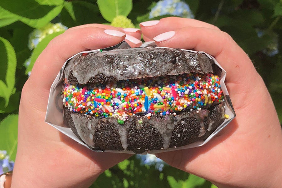 Blackbird Doughnuts Eissandwich auf Schokoladenkrapfen mit Regenbogenstreuseln