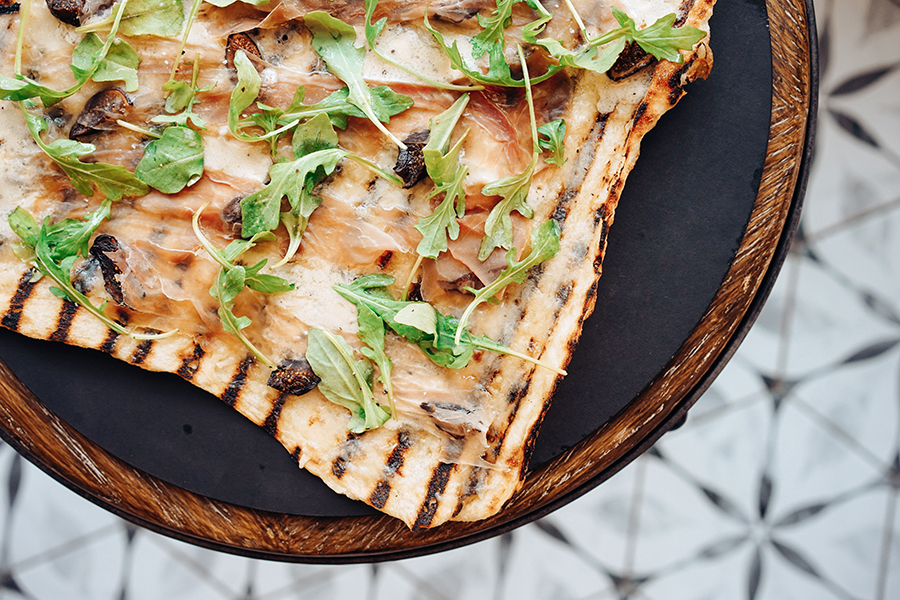 Overhead view of a thin-crust Rhode Island-style pizza with grill stripes on it.