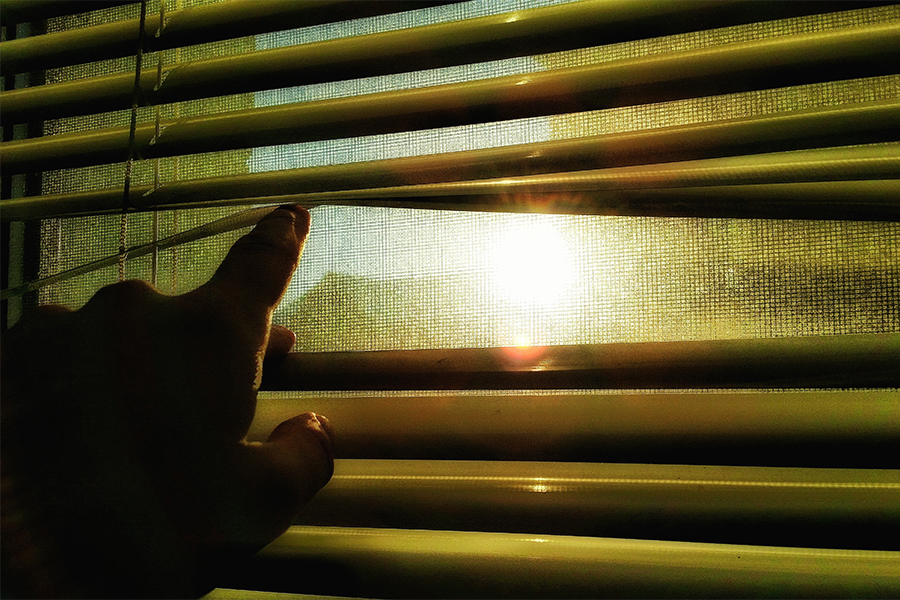 person peering through window blinds