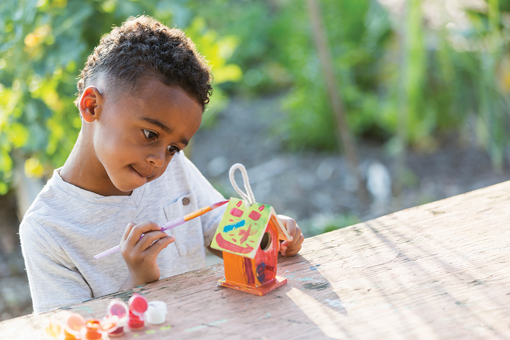 Little boy painting bird house
