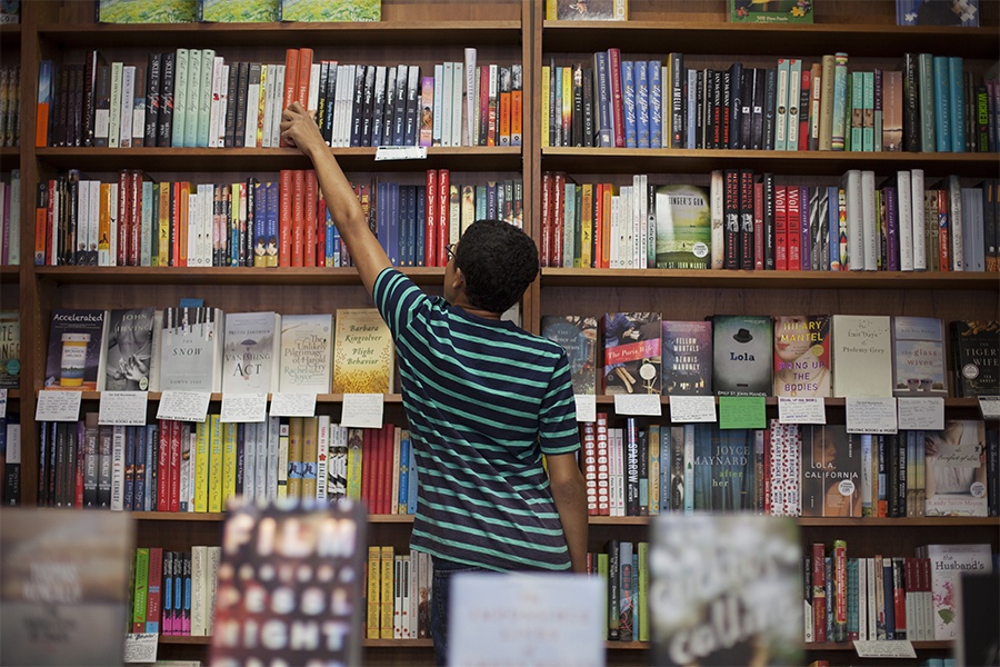 person removing book from shelf