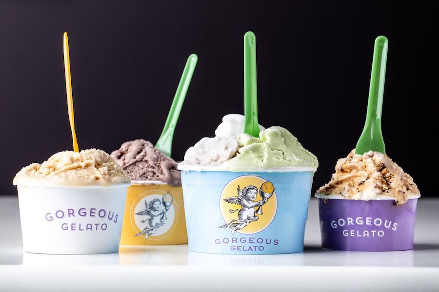 Four paper cups are filled with different flavors of gelato, with little plastic spoons sticking up from each.