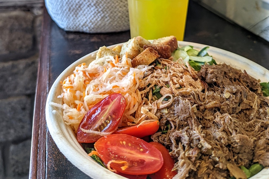 A bowl of shredded beef, tomatoes, cucumbers, and pickled carrots.