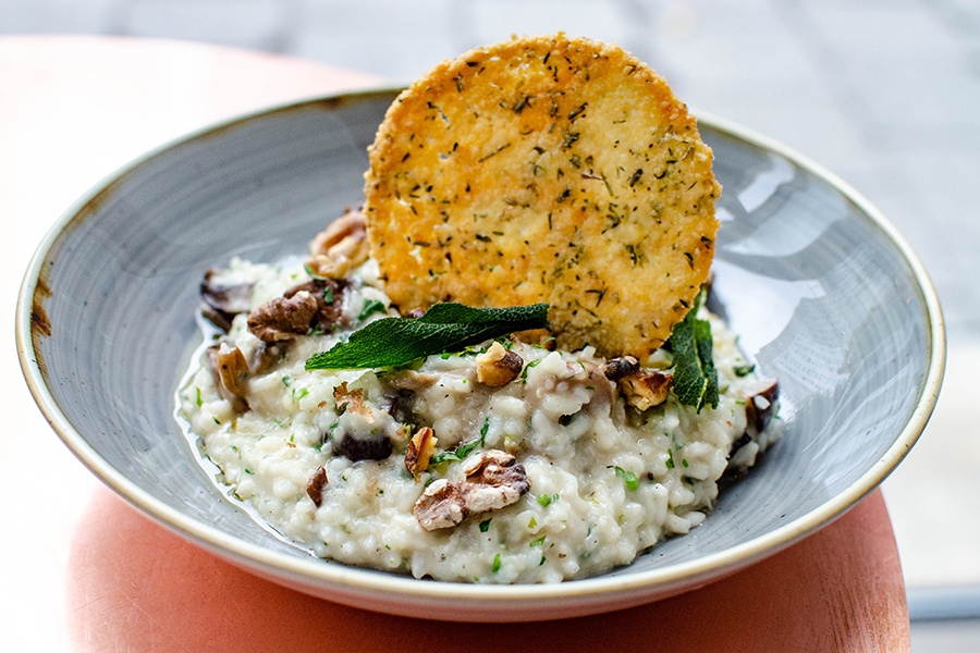 A risotto is studded with walnuts, herbs, and a round cracker.