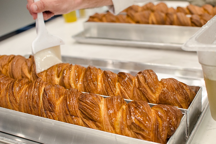 Two long loaves of babka are brushed with a clear glaze.