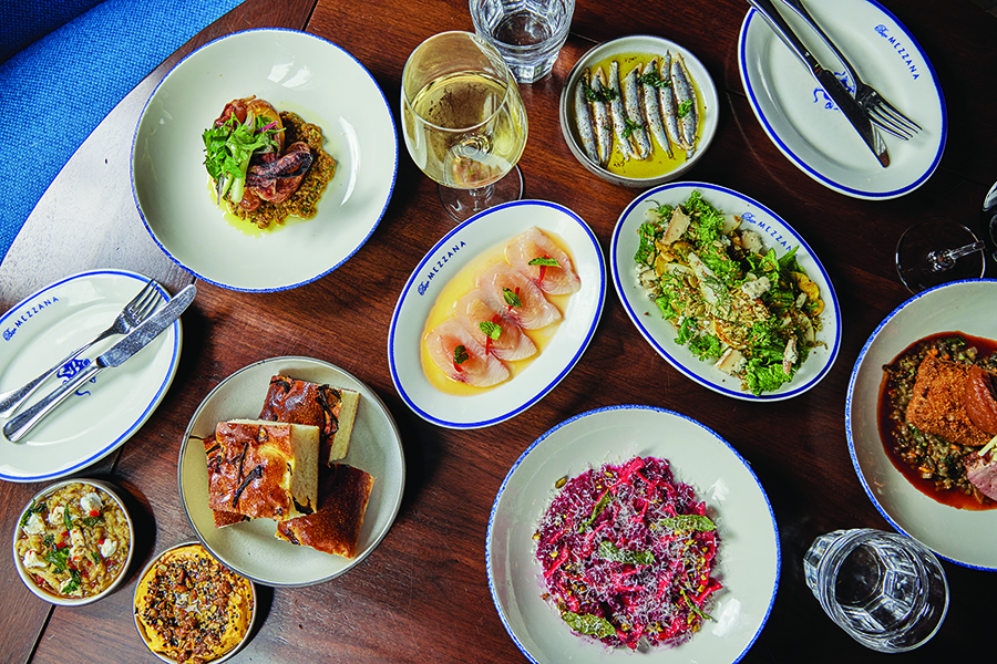 Overhead view of a table full of Italian food, including crudo, anchovies, pasta, and more.