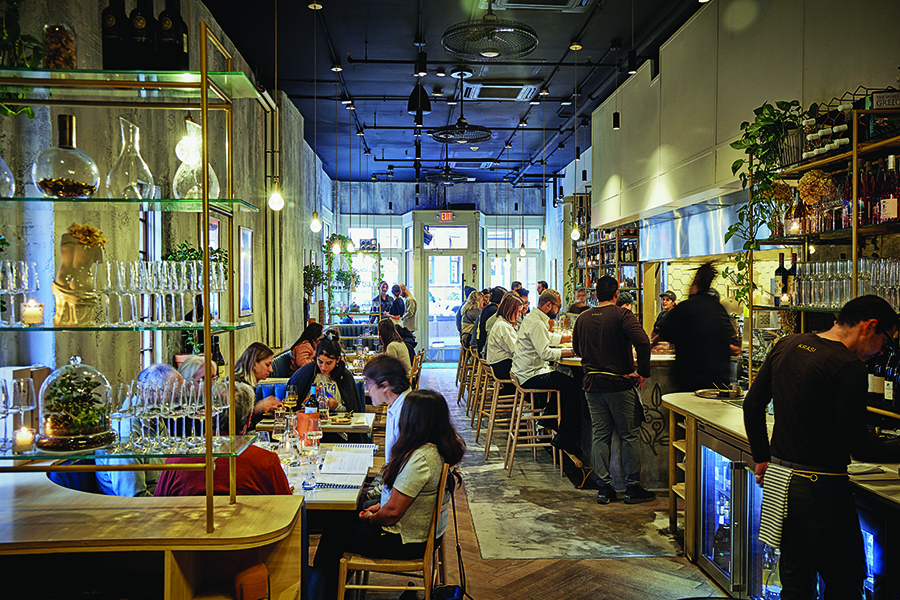 Interior view of a restaurant that toes the line between upscale and rustic, with grayish walls and conspicuous wine paraphernalia.