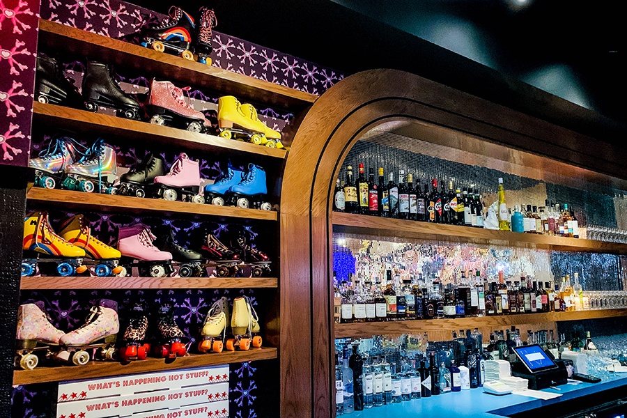 Shelving next to a restaurant's bar are filled with colorful pairs of roller skates.
