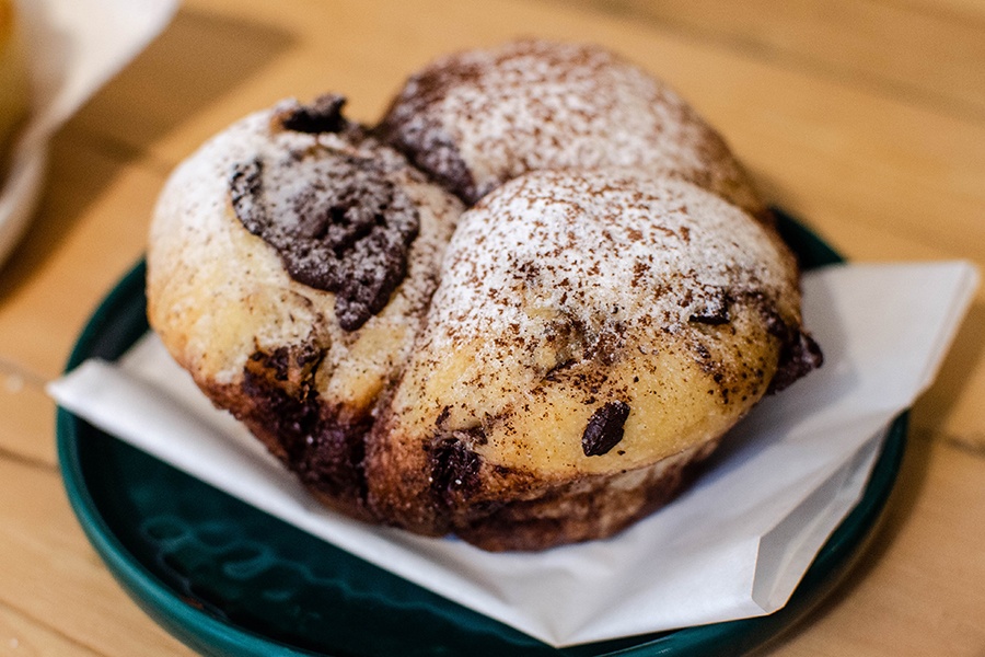 A large brioche-style bun that pulls apart into three is studded with chocolate chunks and dusted with powdered sugar and cocoa powder.