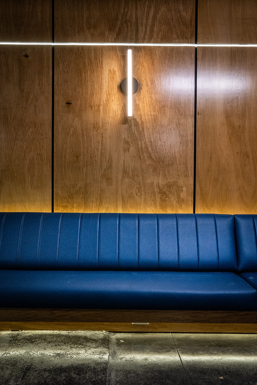 A blue banquette lines a wood-paneled wall.