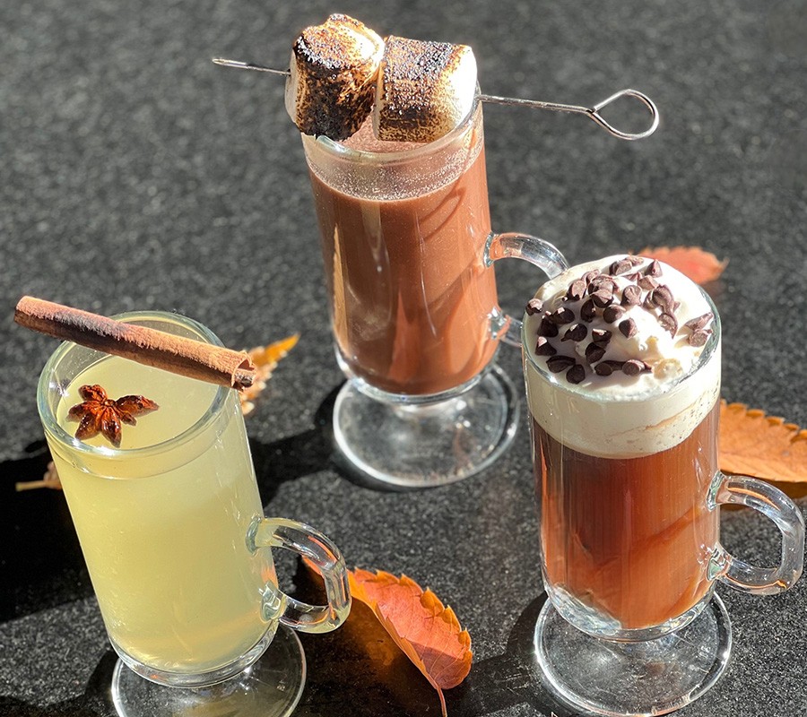 An overhead shot of three cocktails in glass mugs, one topped with marshmallows.
